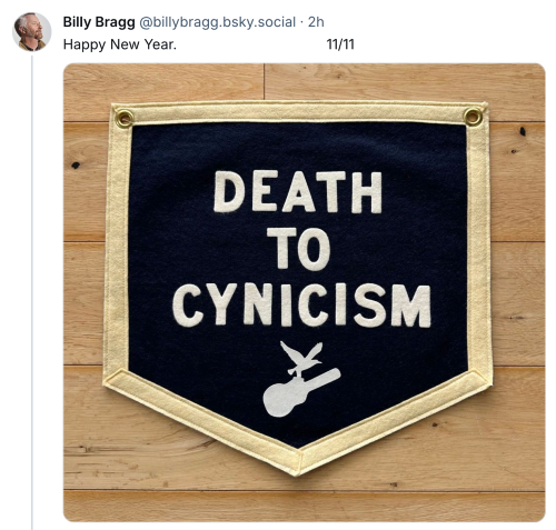 Bluesjy post from Billy Bragg saying "Happy New Year" beneath which is a photo of a fabric patch which reads "DEATH TO CYNICISM" with the logo of a bird flying with a guitar" 